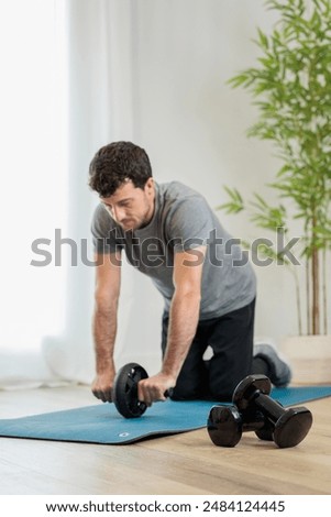 Young man training abs using roller at home gym