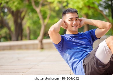 Young Man Training And Doing Sit Ups  In Park