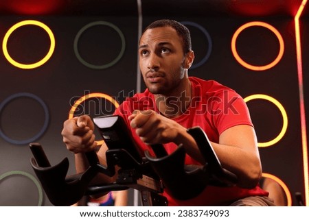 Young man training on exercise bike in fitness club