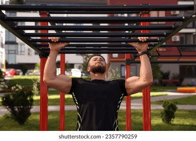 Young man training on monkey bars at outdoor gym - Powered by Shutterstock