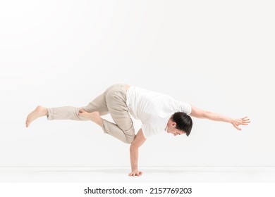 A Young Man Trains Balance In A Gymnastic Stand. Training At Home. Power Gymnastics. Break Dance Air Baby Posture.