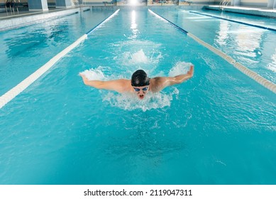 A young man trains and swims in a modern swimming pool. Sports development. Preparation for competitions, and a healthy lifestyle. Water treatments and a healthy lifestyle. - Powered by Shutterstock