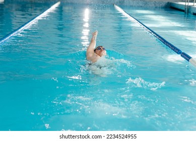 A young man trains and swims in a modern swimming pool. Sports development. Preparation for competitions, and a healthy lifestyle. Water treatments and a healthy lifestyle. - Powered by Shutterstock