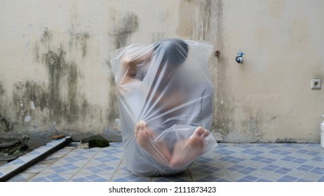 Young Man with a transparent plastic bag wraping his body. suffocate. face in a plastic bag, strangulation