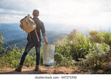 Young Man Traveler with map backpack relaxing outdoor with rocky mountains on background Summer vacations and Lifestyle hiking concept.