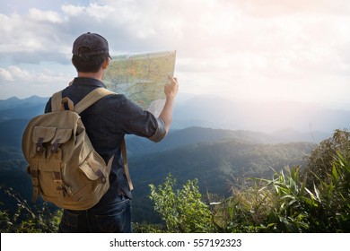 Young Man Traveller mit Karte Rucksack entspannend draußen mit felsigen Bergen auf dem Hintergrund Sommerurlaub und Lifestyle Wanderkonzept.