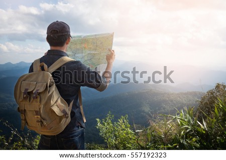 Young Man Traveler with map backpack relaxing outdoor with rocky mountains on background Summer vacations and Lifestyle hiking concept.
