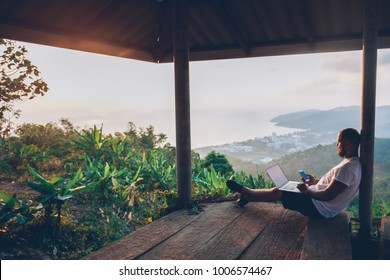 Young man traveler using laptop computer while enjoying beautiful tropical sunset in Thailand. Freelancer guy working on freelance on netbook during vacation holidays in summer. Male adventure blogger - Shutterstock ID 1006574467