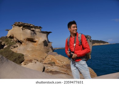 A young man travelling on stony area. Landscape  photographer  with the camera in his hands walking on rocky terrain and wearing backpack
