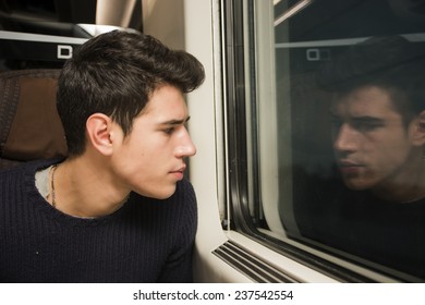 Young Man Travelng In Train Looking Out Of Window Thinking Or With Bored Expression