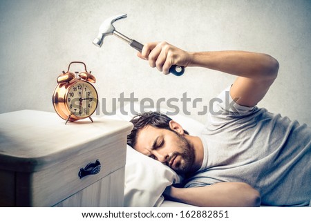 young man tries to break the alarm clock with hammer