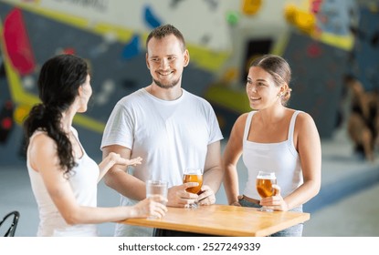 Young man and two young women chat at table on climbing wall after workout - Powered by Shutterstock