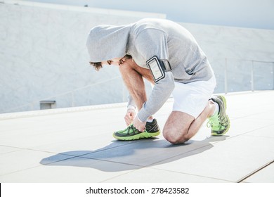 Young Man Tying His Shoe Lace In Middle Of Rushing