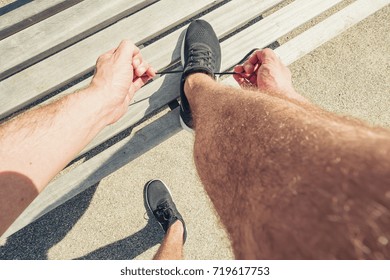 Young Man Tying Laces Of Running Shoes Before Training