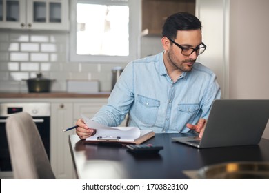 Young Man Typing On A Laptop And Doing Paperwork From Home.