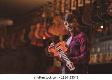 Young man with a ukulele in a music store - Powered by Shutterstock