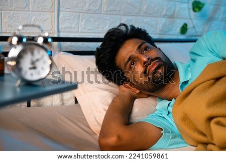 young man unable to sleep during night at bedroom - concept of suffering from insomnia, sleeplessness and family problems