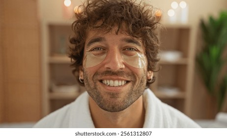 Young man with under-eye patches smiling in a spa room, showcasing a wellness and beauty treatment in an indoor setting. - Powered by Shutterstock