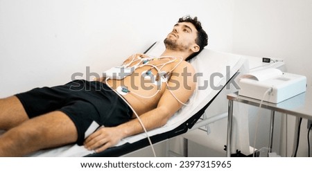 A young man undergoes an electrocardiogram test to diagnose heart disease in a hospital ward. electrocardiograph. Concept of ECG or EKG, electrocardiogram in young people.