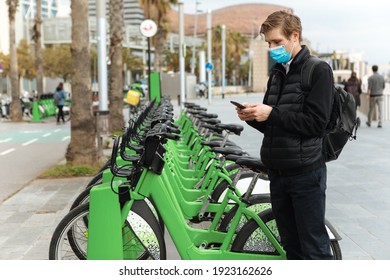 Young Man Unlocks Bicycle With His Mobile Phone. Electric Bicycle New Way City Mobility. Green Transportation. Sustainable Climate Neutral Cities Goals. Ecology Mobility Sustainability Transportation