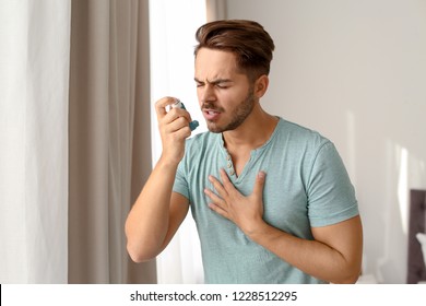 Young Man Using Asthma Inhaler At Home