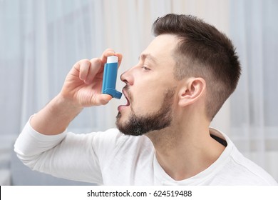 Young Man Using Asthma Inhaler At Home