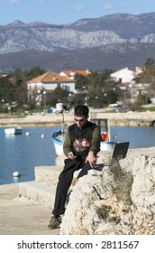young man using a cell phone and laptop