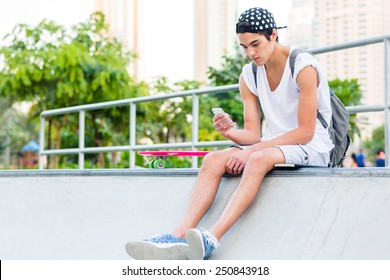 Young man using a cellphone while sitting at the skatepark. - Powered by Shutterstock