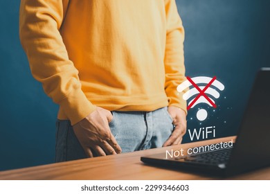 Young man using a computer laptop to connect to wifi in his home but wifi not connected, and waiting to loading digital game data form website, concept technology of waiting for connect to wifi.