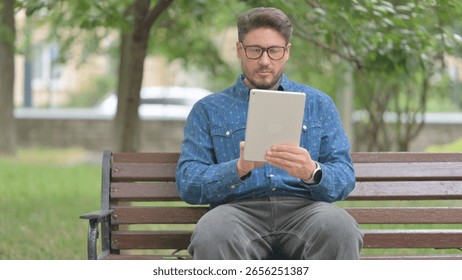Young Man Using a Digital Tablet Outdoor on Bench