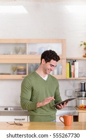 Young man using digital tablet in kitchen