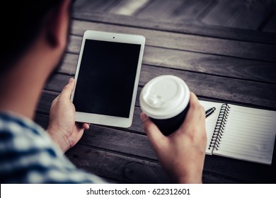 Young man using digital tablet while drinking Coffee sitting at home garden, Relaxing in the morning.