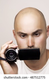 Young man using a digital video camera in office garden.