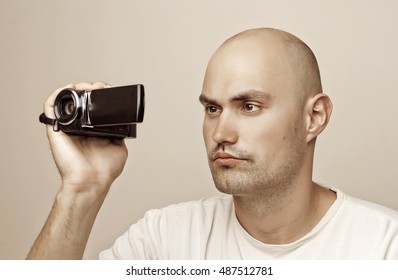 Young man using a digital video camera in office garden.