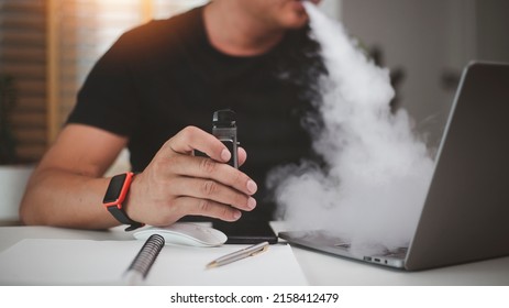 young man using disposable electronic cigarette at table in office - Shutterstock ID 2158412479