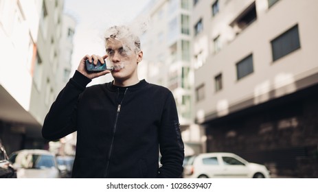 Young Man Using Electronic Cigarette To Smoke In Public Places.Smoke Restriction, Smoking Ban.Using Vaping Device With Flavoured Liquid.Smoking Habit, Nicotine Addict, Tobacco Industry