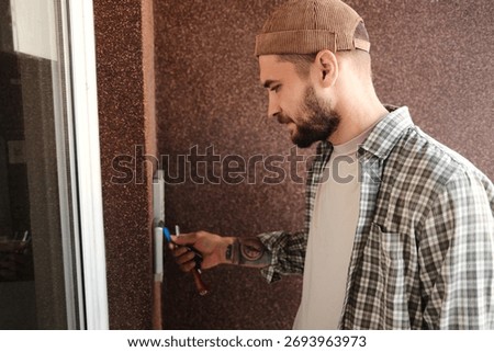 Young man using an electronic key fob to unlock a modern apartment door. Concept of security, access control, and urban lifestyle