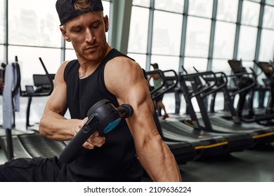 A Young Man Is Using And Enjoying Percussion Massage Gun To Relax And Relief The Pain In Body And Muscles In The Gym