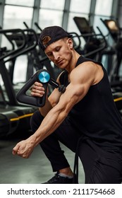 A Young Man Is Using And Enjoying Percussion Massage Gun To Relax And Relief The Pain In Body And Muscles In The Gym