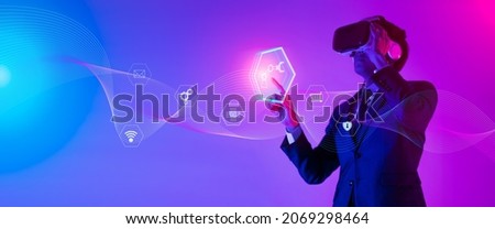Young man using glasses of virtual reality on dark background. Smartphone using with VR headset,virtual reality,future technology concept.Asian man using VR glasses in colorful neon lights.