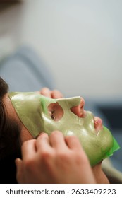 Young man using green face mask with hydrating effect. Male beauty procedures. Nourishing and pampering his skin with a hydrating and moisturizing facial mask
