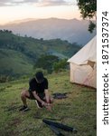 Young man using hammer setting up tent for camping on hill