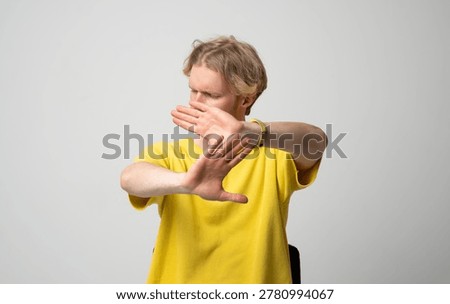 Young man using hands gesture signaling stop and refusal, creating a boundary, rejecting, denying, abstaining, defending, and protecting personal space with a blocking pose