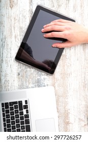 A young man using his laptop computer and various other devices on a desktop.	