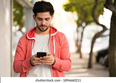 Young Man Using His Mobile Phone Outdoors.