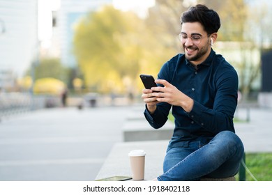 Young man using his mobile phone outdoors. - Powered by Shutterstock