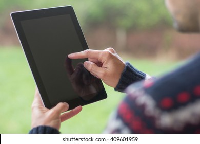 A young man is using his tablet in a green nature background