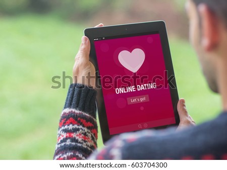 A young man is using his tablet outdoor and using online dating app