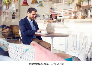 Young Man Using Laptop At A Cafe