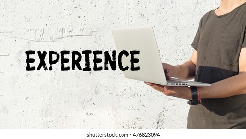 Young man using laptop and EXPERIENCE concept on wall background